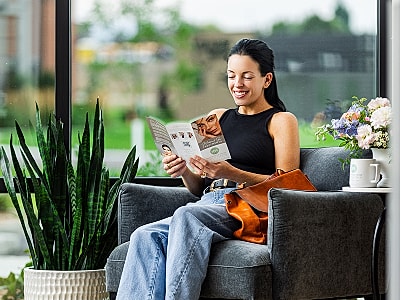Woman reading magazine in cozy indoor setting.
