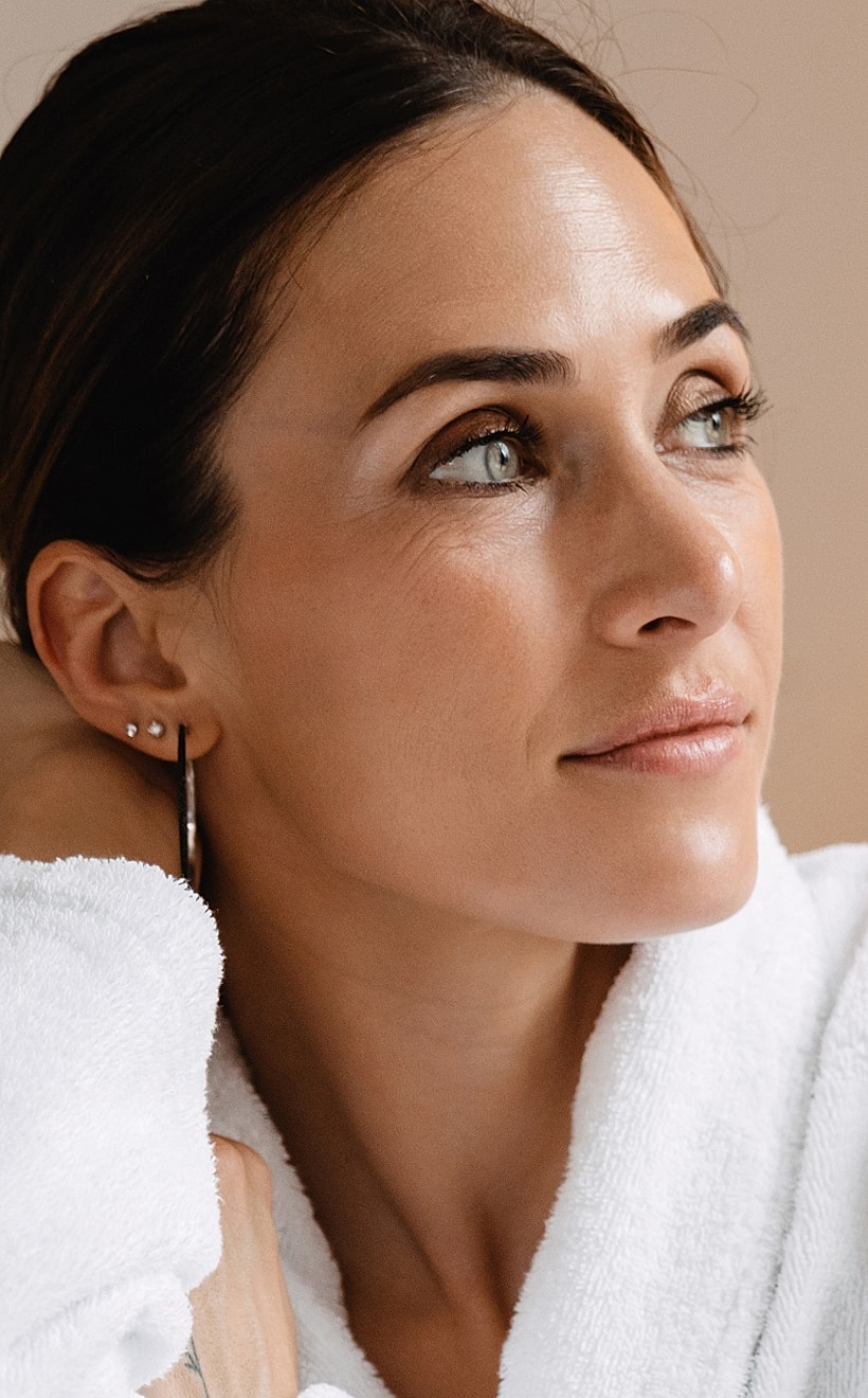 Woman in a white robe looking thoughtfully.