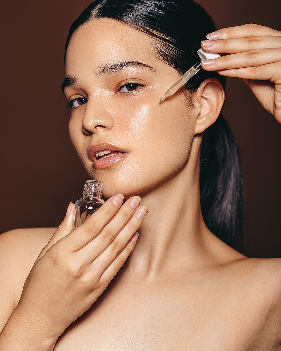Woman applying serum to her face.