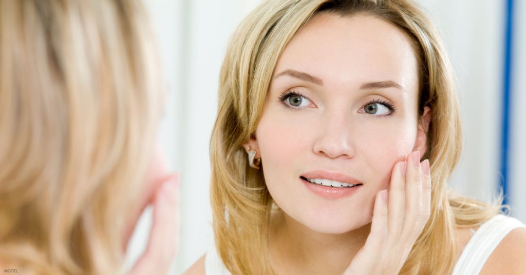 Woman looking in mirror wondering if she is ready for a facelift
