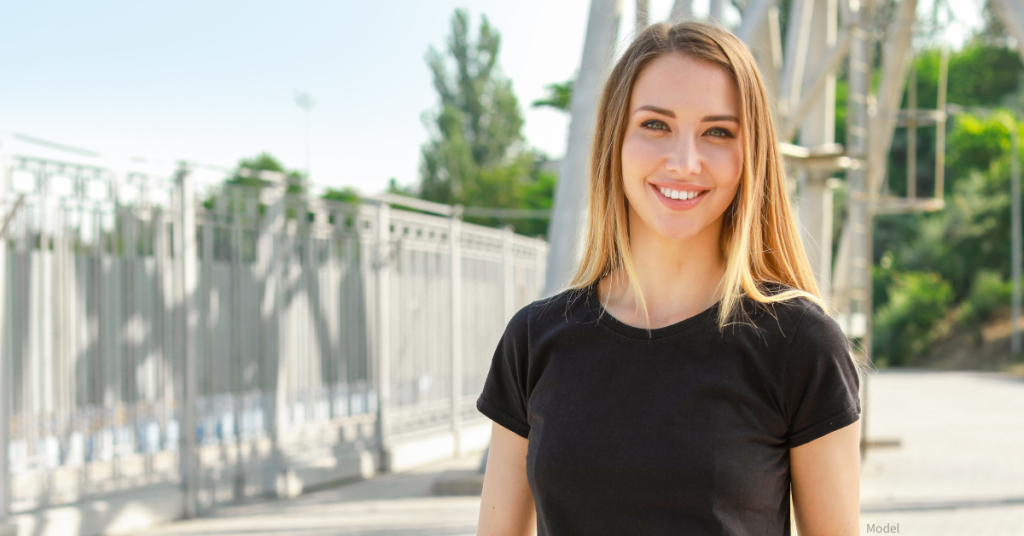 Woman (model) smiling outdoors in the sun.