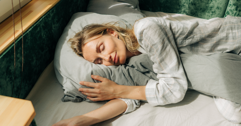Woman (model) peacefully sleeping on her side in bed.